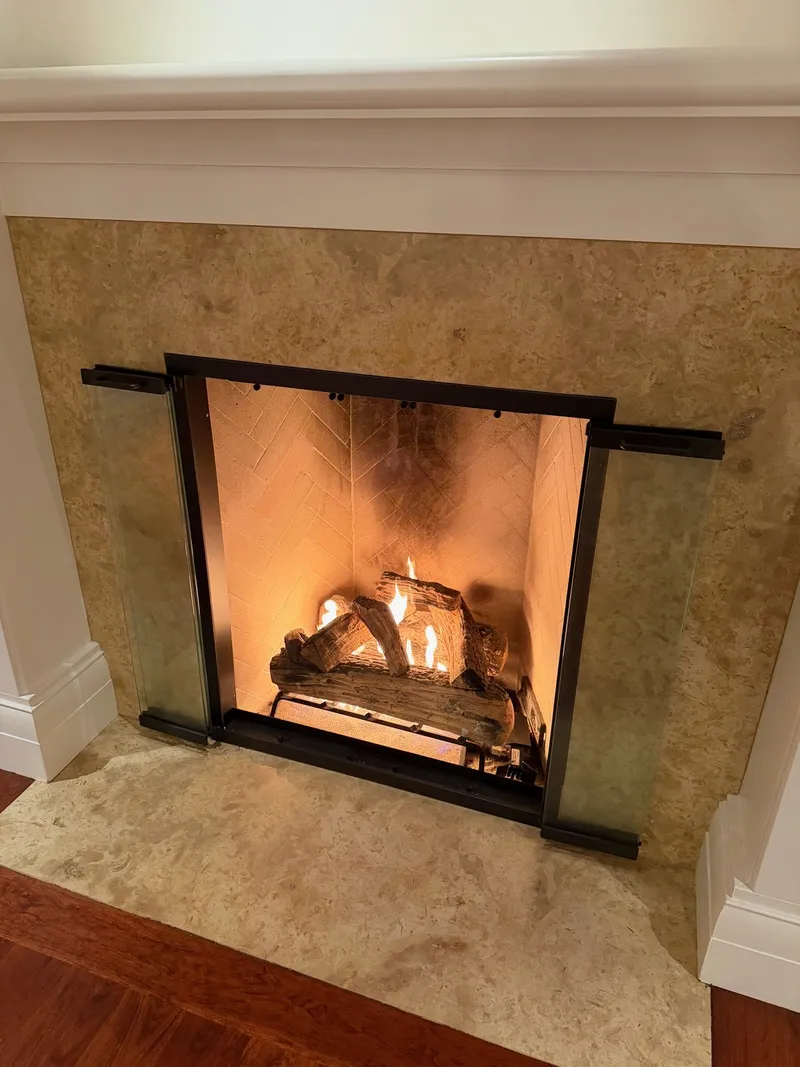 Completed gas log installation — glass doors open, herringbone firebox